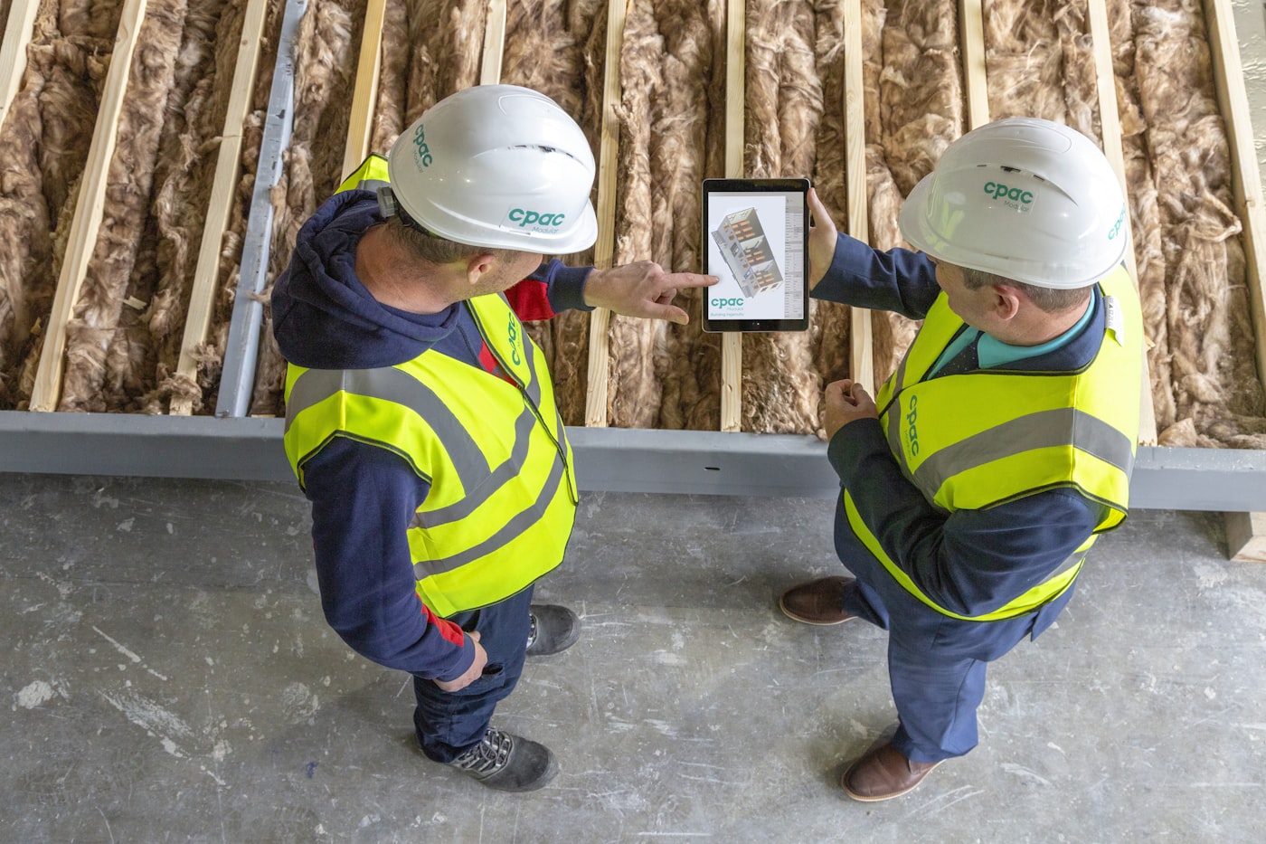 Construction contractor reviewing project plans on a tablet at a job site.