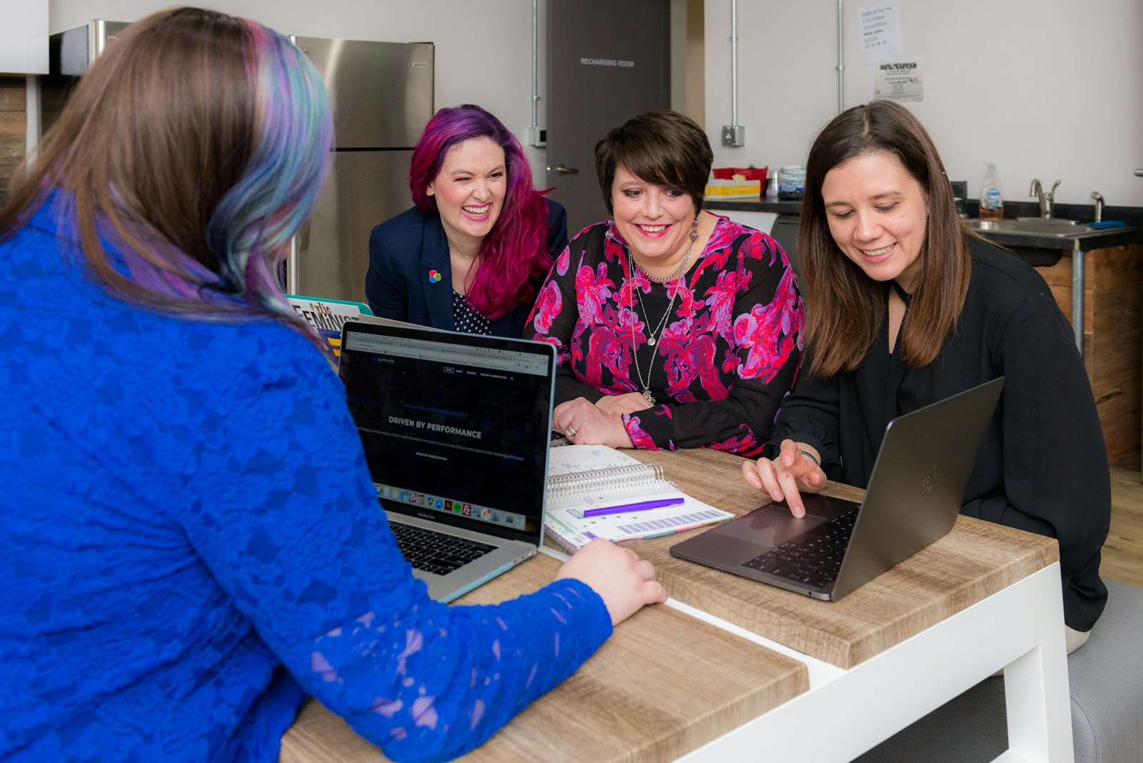 Diverse nonprofit team collaborating around laptops in an office, working together on community programs and operations.
